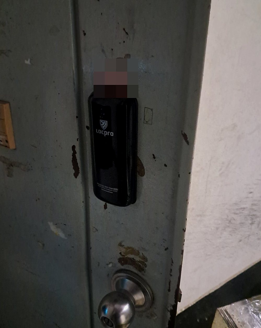 검단구 검단동 출장 — 녹 자국 있는 청회색 철문에 붙은 검은 외장형 도어락과 아래쪽 은색 둥근 손잡이