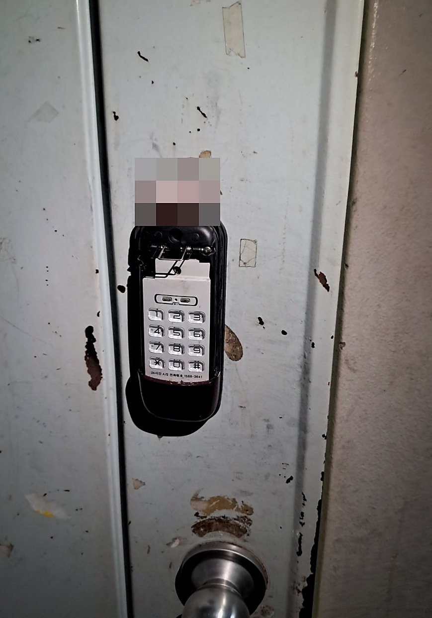 검단구 오류왕길동 출장 — 연한 청회색 철문에 달린 번호키, 열린 덮개 안의 흰 번호 버튼과 아래쪽 은색 둥근 손잡이