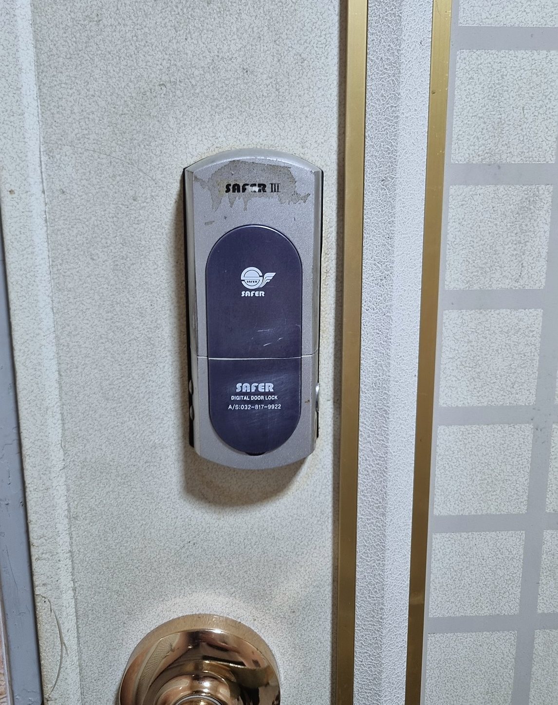 검단구 원당동 출장 — 크림색 문에 단 은색 덮개형 디지털 도어락, 윗부분 표면이 벗겨진 모습과 아래의 황동빛 둥근 손잡이